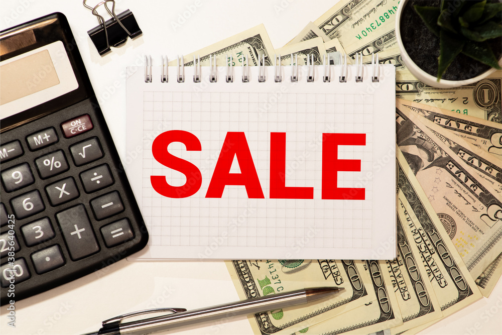 Fototapeta premium word sales written by male hand on white paper board on financial documents, top view.