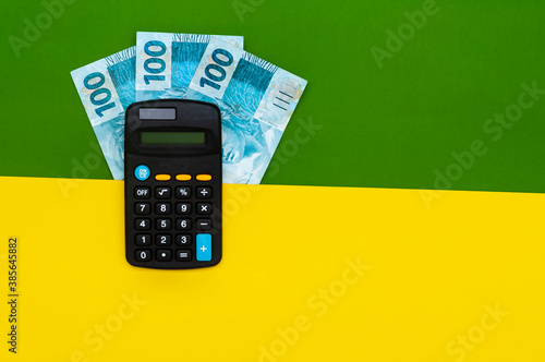 Brazilian money in wallet, with notepad and calculator. Finance and salary concept. Economy of Brazil. Green and yellow background. Three hundred reais