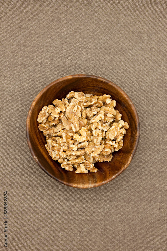 Walnuts in wooden bowl on brown background. Walnuts in wooden bowl on brown background.
