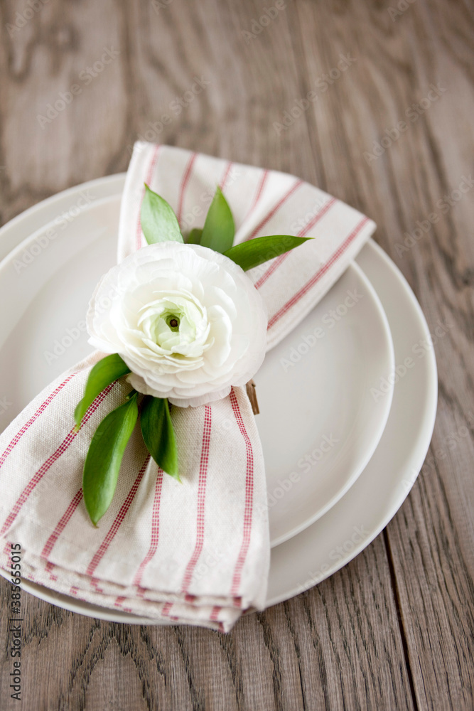 Dinner place setting with white ranunculus.