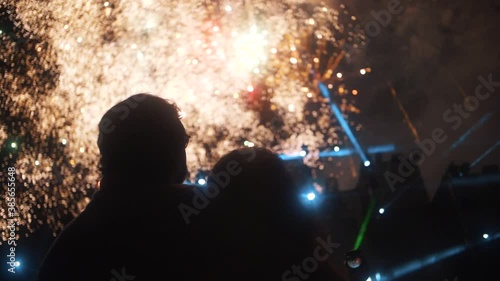 Couple enjoying Fireworks in the sky during concert celebration  - night-time slow motion photo