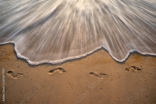 Foto Waves of the sea and footprints on the sandy beach.