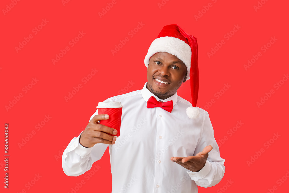African-American man in Santa hat and with coffee on color background African-American man in Santa hat and with coffee on color background