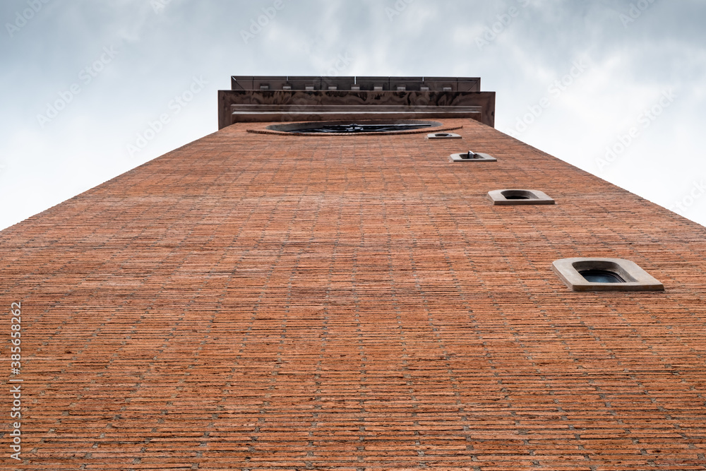 Low angle view of city clock tower built from orange bricks against white sky background.
Low angle view of city clock tower built from orange bricks against white sky background.