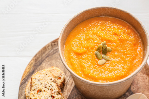 Tasty pumpkin cream soup in cup on table, closeup