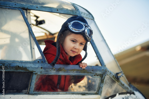 Portrait of a cute little girl in the cockpit of an old plane. Childhood dreams of aviation.