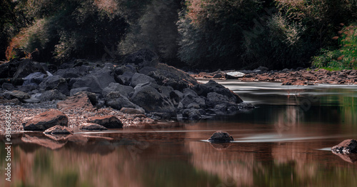Fototapeta Naklejka Na Ścianę i Meble -  Long exposure reflected of rocks and trees on the river in autumn.