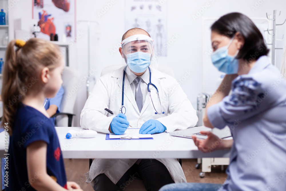 Doctor wearing face mask agaisnt coronavirus explaining diagnosis to mother of child. Health pediatrician specialist providing health care services consultations treatment. Doctor wearing face mask agaisnt coronavirus explaining diagnosis to mother of child. Health pediatrician specialist providing health care services consultations treatment.