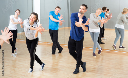 Cheerful people practicing vigorous lindy hop movements in dance class.
