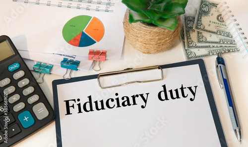 Paper with Fiduciary duty on the table, calculator and money photo