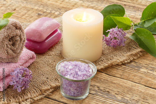 Towels  soap  candle and lilac flowers on wooden background.