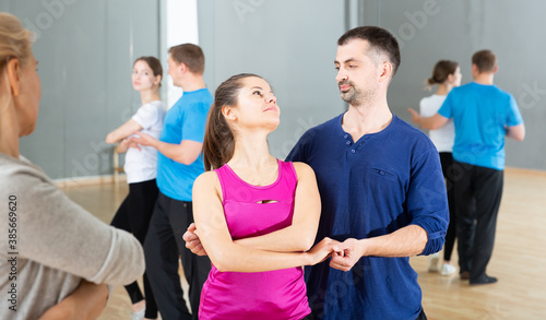 Young sporty woman enjoying bachata dance with partner in dancing class