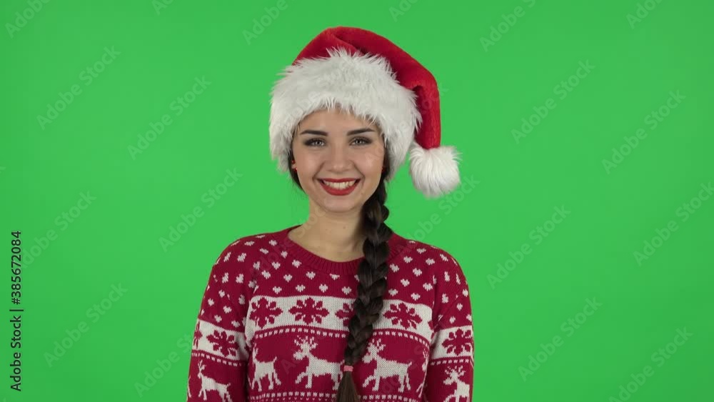 Portrait of sweety girl in Santa Claus hat is smiling while looking at camera. Green screen Portrait of sweety girl in Santa Claus hat is smiling while looking at camera. Green screen