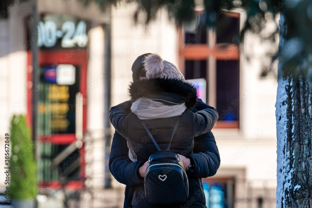 happy couple hugging while standing together on a street in the city happy couple hugging while standing together on a street in the city