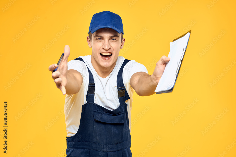 Man in working uniform documents rendering of services delivery service yellow background Man in working uniform documents rendering of services delivery service yellow background