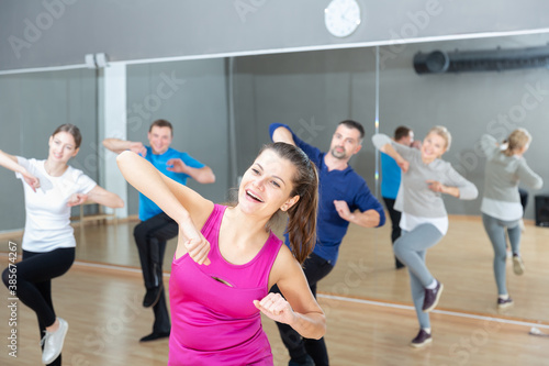 Cheerful young woman enjoying active dances in modern dance studio.
