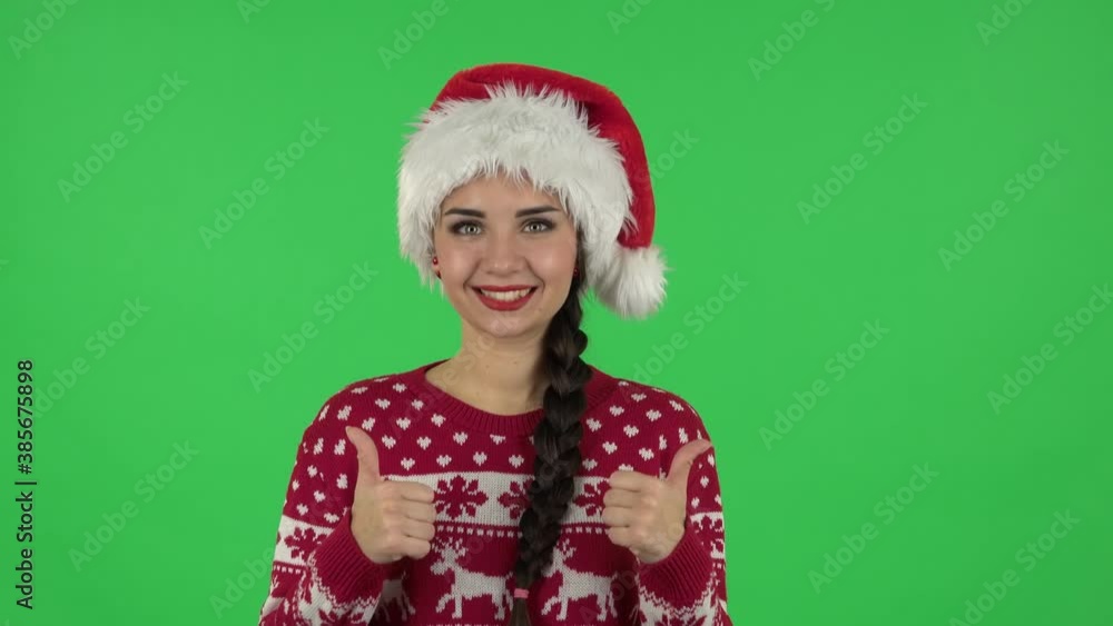 Portrait of sweety girl in Santa Claus hat is saying wow, waves her head approvingly and showing thumb like. Greenscreen Portrait of sweety girl in Santa Claus hat is saying wow, waves her head approvingly and showing thumb like. Greenscreen