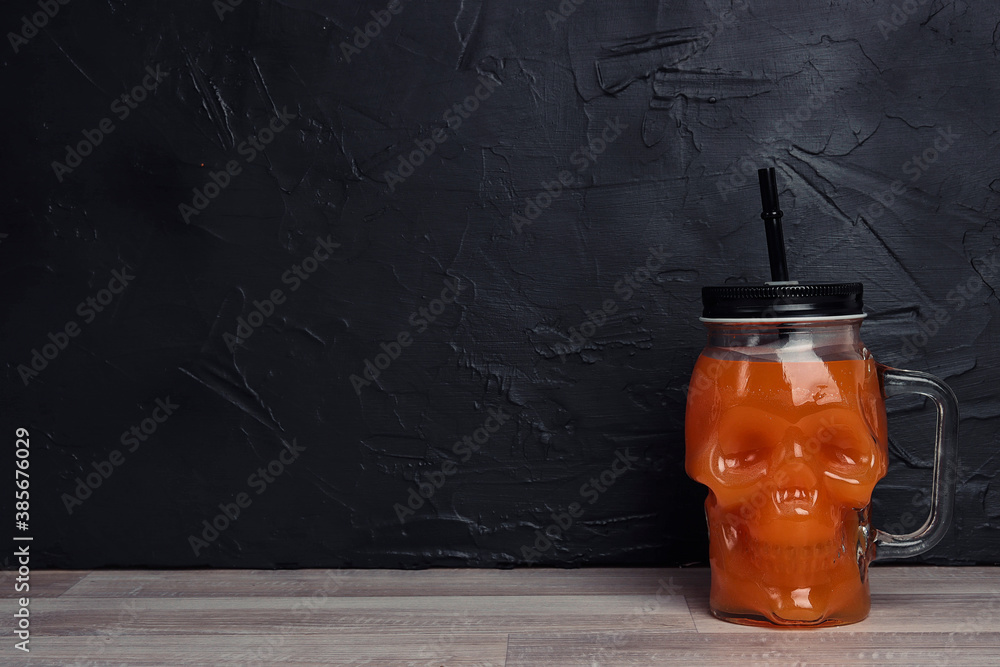 Orange Halloween cocktail in skull glass jars on black background. - obrazy, fototapety, plakaty 