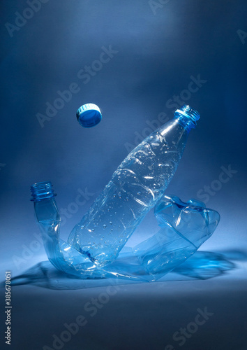 Blue plastic bottles on a blue background. Levitation of the lid. Concept of waste disposal. Copy space