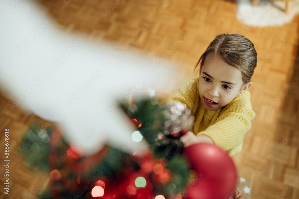 Above view of a girl decorating Christmas tree. Above view of a girl decorating Christmas tree.