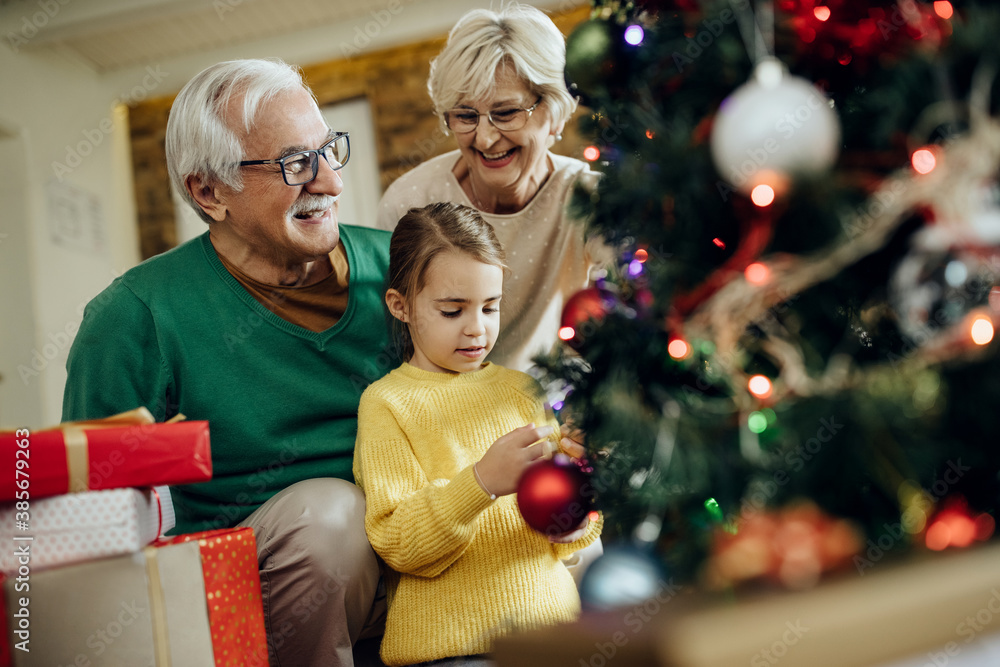 Happy senior couple and their granddaughter decorating Christmas tree at home. Happy senior couple and their granddaughter decorating Christmas tree at home.
