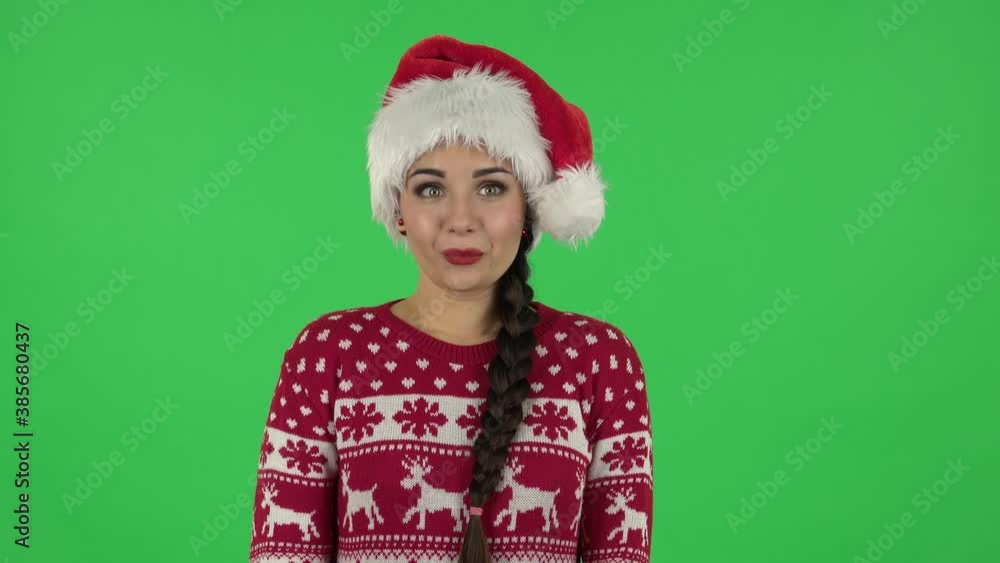 Portrait of sweety girl in Santa Claus hat is saying oops and shrugging and biting lips. Green screen Portrait of sweety girl in Santa Claus hat is saying oops and shrugging and biting lips. Green screen