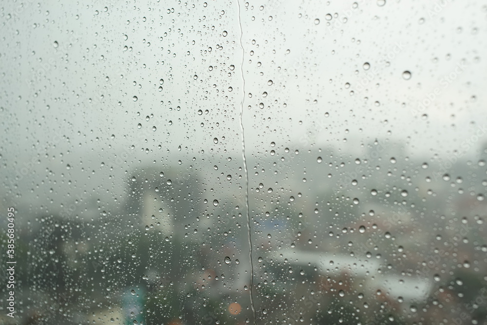 Water drop on glass window with cloudy sky and city on background Water drop on glass window with cloudy sky and city on background