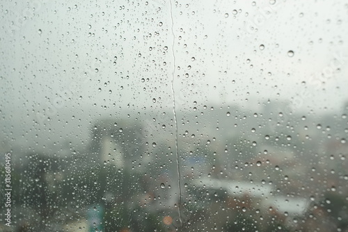 Water drop on glass window with cloudy sky and city on background