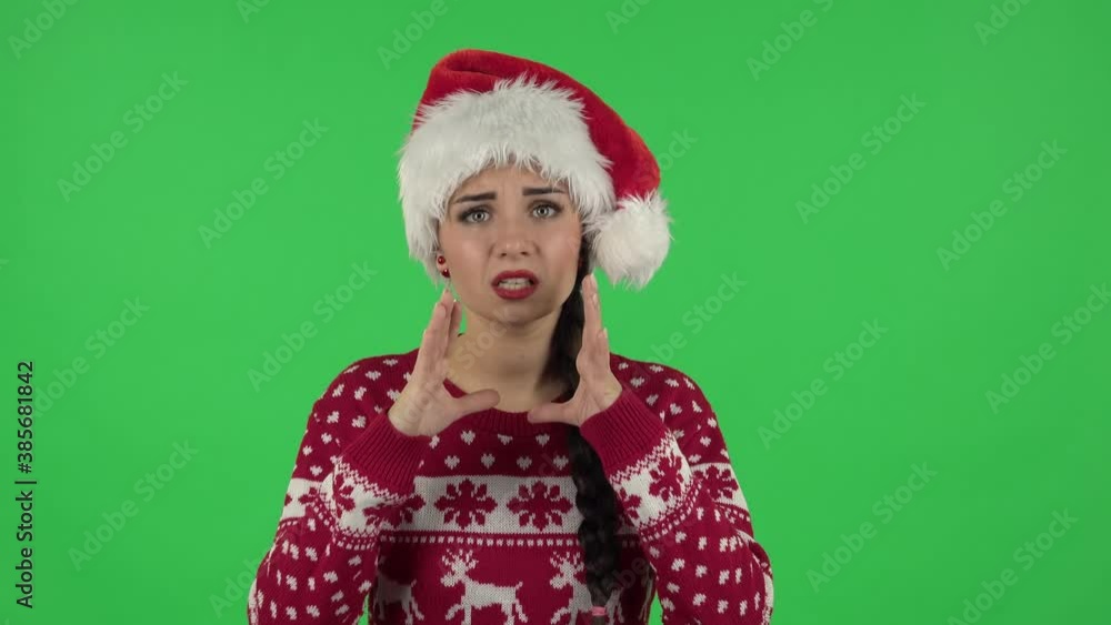Portrait of sweety girl in Santa Claus hat is negatively screaming calling someone. Green screen Portrait of sweety girl in Santa Claus hat is negatively screaming calling someone. Green screen