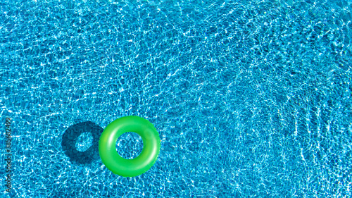 Aerial view of colorful inflatable ring donut toy in swimming pool water from above, family vacation holiday resort background 