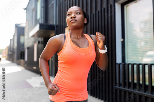 fitness  sport and healthy lifestyle concept - young african american woman running in city