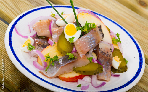 Marinated herring with sliced apples, cucumbers, onion - traditional dish of Norwegian cuisine