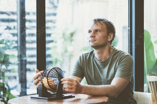 Young serious thoughtful man hold lotto round sphere spins small balls, table loto game as symbol of future problem, life crisis, choice responsibility. Look far away window face expression gesture