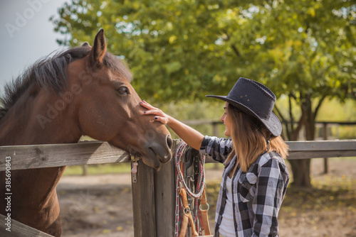 American woman on a horse farm. Portrait of girl in cowboy hat with a horses. Hippotherapy at nature