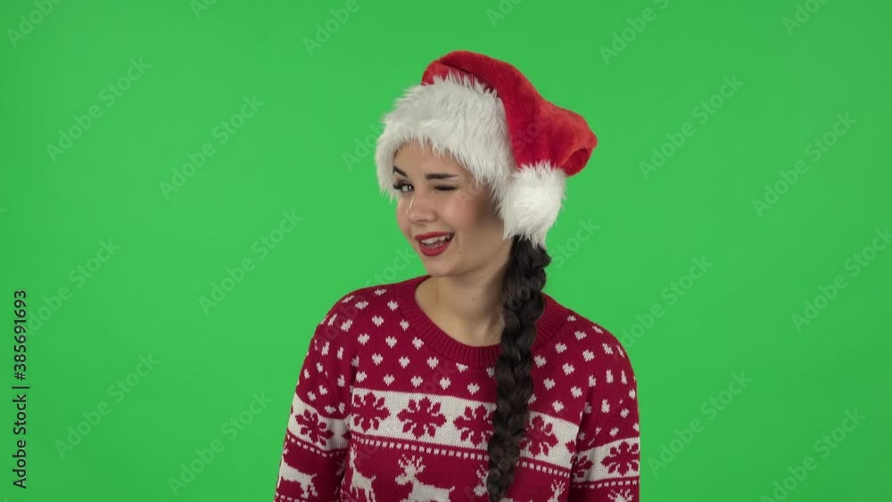 Portrait of sweety girl in Santa Claus hat is smiling broadly and winking. Green screen Portrait of sweety girl in Santa Claus hat is smiling broadly and winking. Green screen
