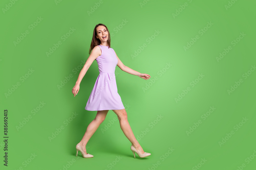 Full size photo of adorable slim young girl lady walking forward empty space look camera toothy smile advert clothes brand wear violet dress isolated pastel green color background Full size photo of adorable slim young girl lady walking forward empty space look camera toothy smile advert clothes brand wear violet dress isolated pastel green color background