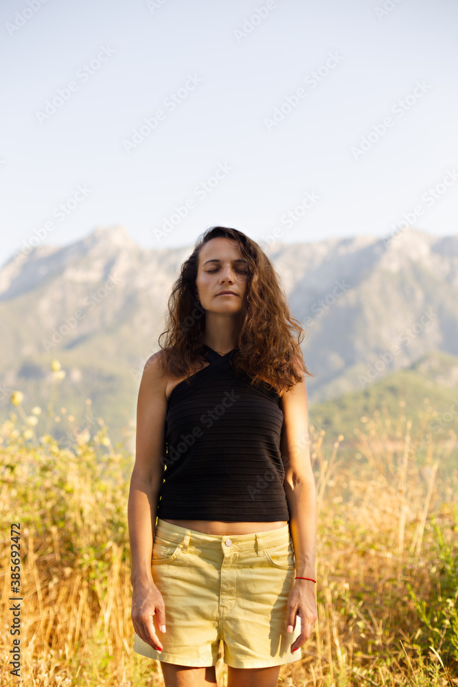 Female with eyes closed with mountains in the background Female with eyes closed with mountains in the background