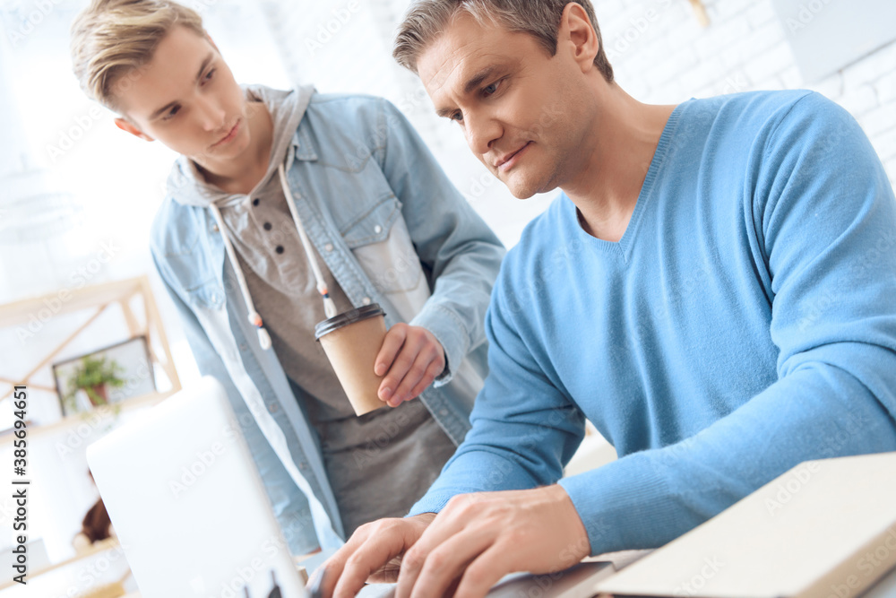 Obraz premium While dad works at computer, son brought coffee. 