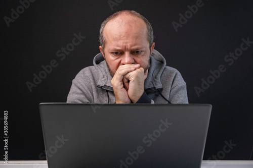 Fotografie Man in hoodie working from home office, worried face expression