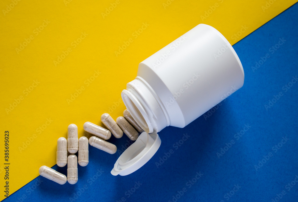 White medical pills with pill box on yellow and blue background White medical pills with pill box on yellow and blue background