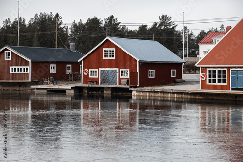 Red boat house in Sweden with reflection on the ice