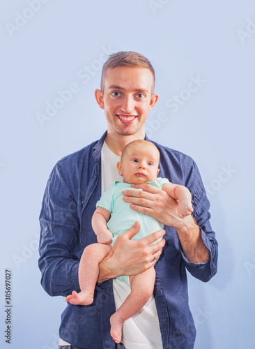 Baby boy in father s arms on blue background