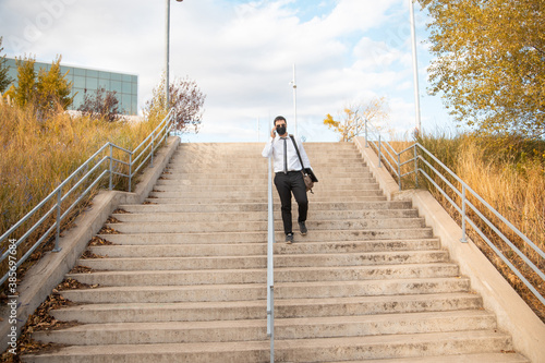 office man walking down park stairs with mask