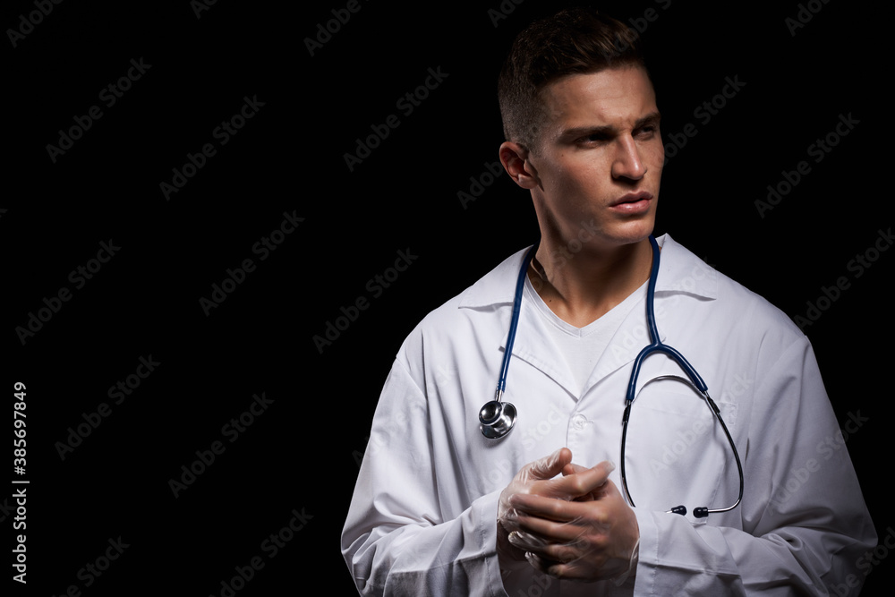 professional doctor in a medical gown with a stethoscope around his neck against a dark background cropped view professional doctor in a medical gown with a stethoscope around his neck against a dark background cropped view