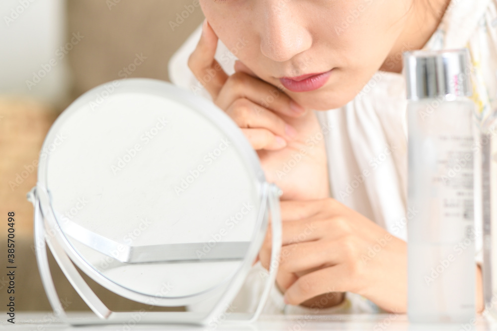 鏡を見ながら肌トラブルに悩む女性