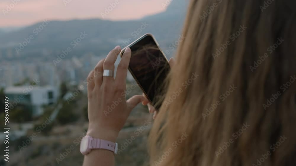 Young woman use smartphone app to make photos or record videos of beautiful scenery, city landscape at sunset. Modern millennial generation z person use technology Young woman use smartphone app to make photos or record videos of beautiful scenery, city landscape at sunset. Modern millennial generation z person use technology