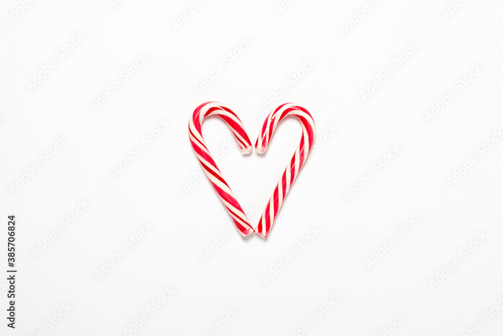 Caramel cane folded in the shape of a heart on a white isolated background. Concept Christmas, New Year, sweets for the holiday. Flat lay, top view