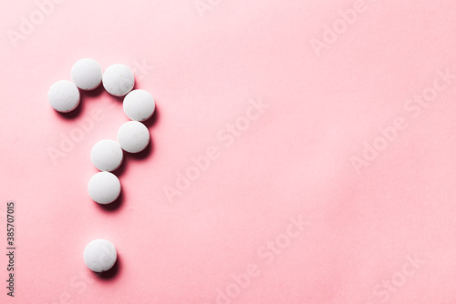 question mark made of white pills on a blue background. treatment choice and idea and question concept.