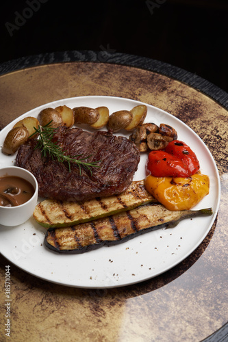 Ribeye steak with fried potatoes. Baked vegetables with beef steak on white plate