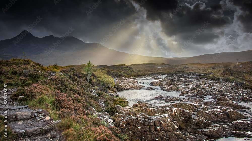 A stormy sky with sun beams over the river Sligachan on the Isle of Skye in Scotland